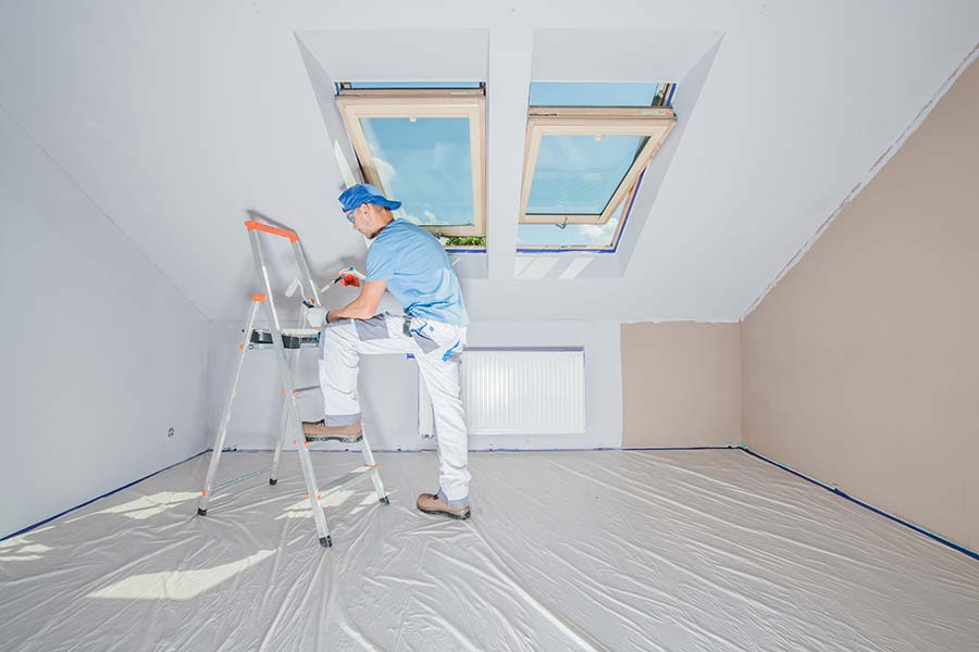 man painting attic room ceiling