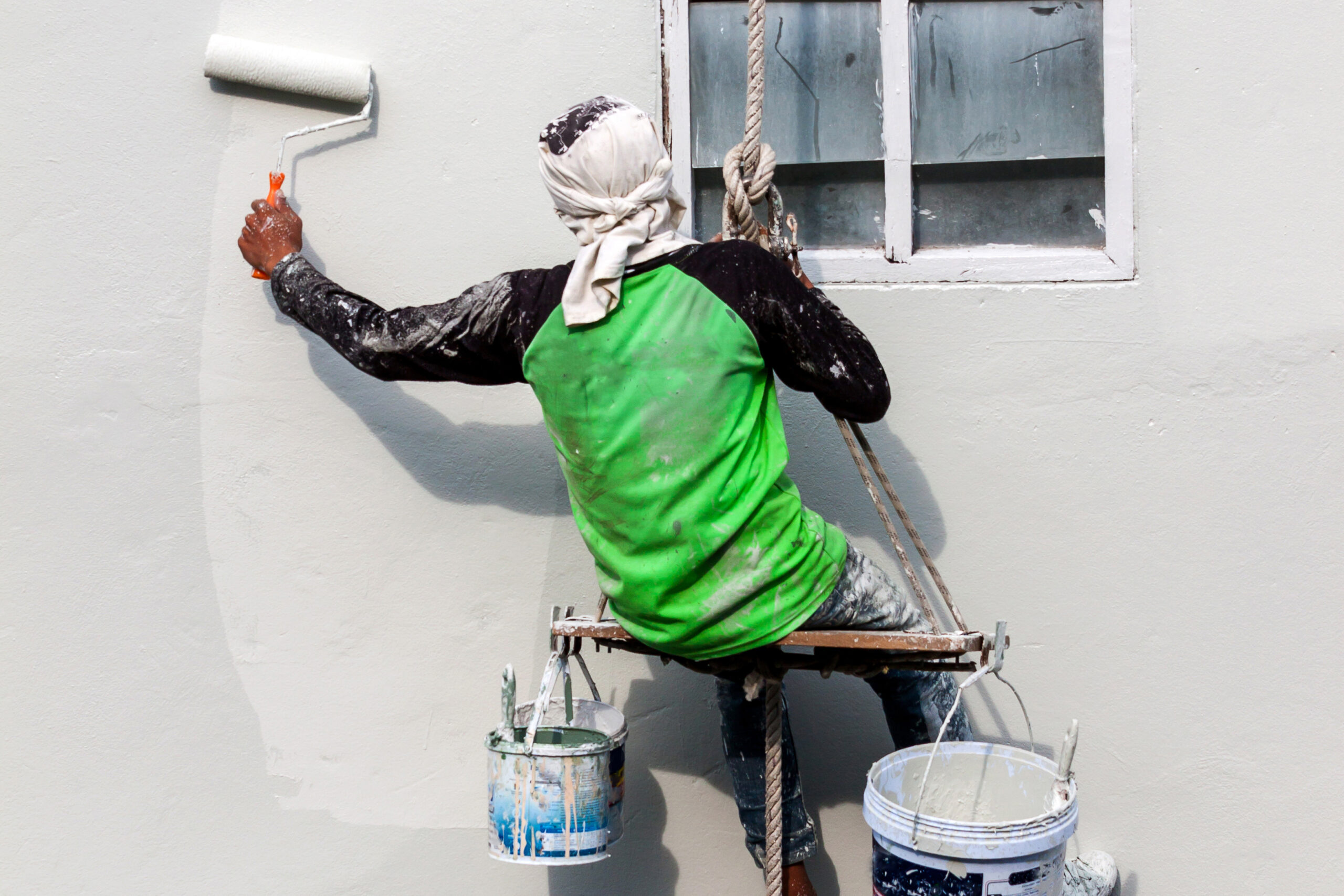 man on scaffold painting an exterior wall